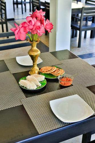 a table with plates of food and a vase with pink flowers at Esprit Bentota in Bentota
