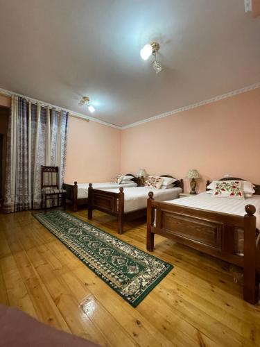 a bedroom with two beds and a rug at Hotel Al Mansur in Bukhara