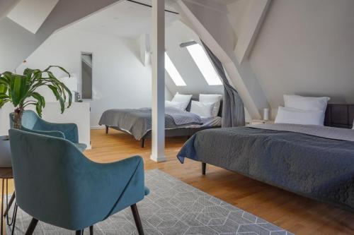 a bedroom with two beds and a chair at Hejm Apart - Design Maisonette-Ferienwohnung "Zugspitze" in Mering