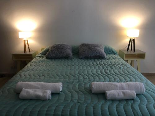 ein großes grünes Bett mit zwei Kissen darauf in der Unterkunft AQUA in Puerto Madryn