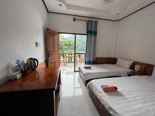 una camera con due letti e una scrivania e una camera con finestra di Nongkhaiw river view a Nongkhiaw