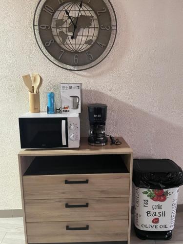 a clock on a wall with a microwave on a cabinet at Chez Tikaf in Saint-Claude