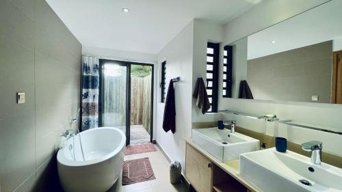 格兰贝伊Villa de luxe, près de la mer et des commerces的带浴缸、水槽和镜子的浴室