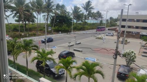 a street with cars parked in a parking lot with palm trees at Estilo Bela Vista 308 in Cabedelo