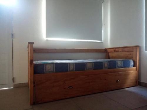 Cama de madera en habitación con ventana en Mangata mono en Mar de Cobo