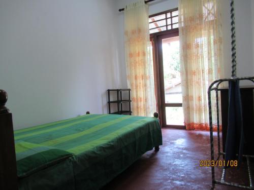 um quarto com uma cama verde e uma janela em pumindu homestay em Matara
