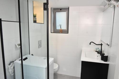 a white bathroom with a toilet and a sink at Deluxe Basement Apartment Bahai's Garden in Haifa