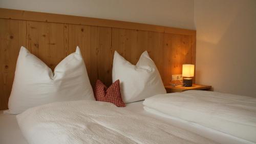 una camera da letto con letto, lenzuola e cuscini bianchi di Ferienwohnungen Schlosshäusl a San Lorenzo di Sebato