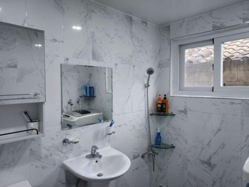 a white bathroom with a sink and a window at Grandmother's Vegetable garden in Anseong