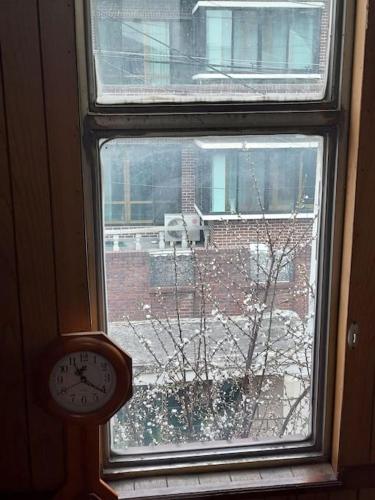 a window with a clock in front of a snow covered yard at Grandmother's Vegetable garden in Anseong