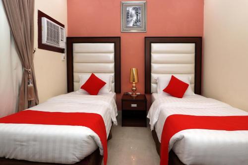 two beds in a room with red and white sheets at Jubail Rose in Al Jubail