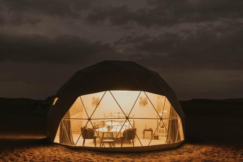 a tent with a table and chairs in the desert at Luxury Desert Camp Oman in Al Wāşil