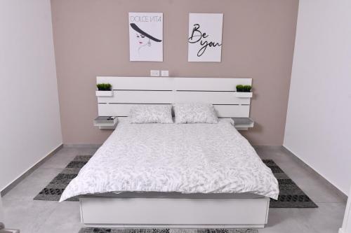 a bedroom with a white bed and a white headboard at Deluxe Basement Apartment Bahai's Garden in Haifa