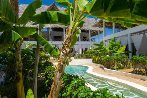 a pool in the middle of a resort with palm trees at Rafiki Village in Watamu