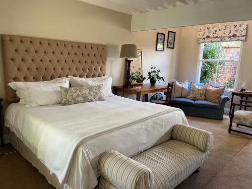 a large bedroom with a large bed and a couch at Fiddlewood Fields Guest House in Grahamstown