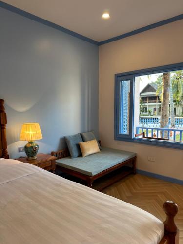 - une chambre avec un lit, une chaise et une fenêtre dans l'établissement Sadakham Hotel, à Luang Prabang