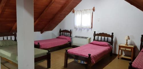 Habitación con 3 camas con sábanas rosas y ventana. en DORMIS La Faustina en San Rafael