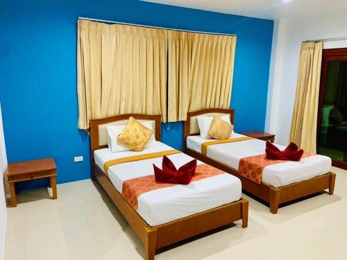 Dos camas en una habitación con paredes azules. en Phumin Apartment, en Ko Lanta