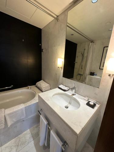 a bathroom with a sink and a tub and a mirror at Dubai Mall Highest Floor With Burj Khalifa View Residence - Formerly Address Dubai Mall in Dubai