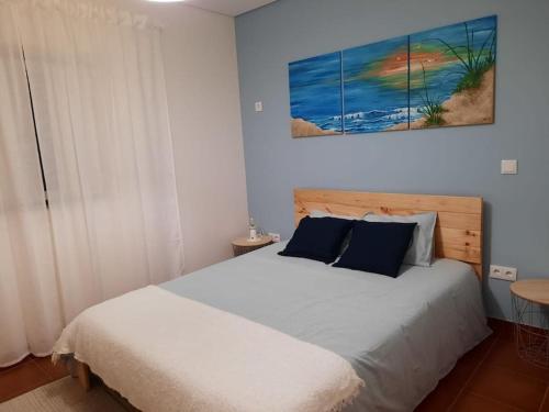 a bedroom with a bed and a painting on the wall at Casa da Dina in Ponte de Lima