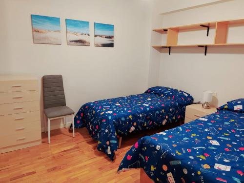 a bedroom with two beds and a desk and a chair at Apartamento Jarauta 50 in Pamplona