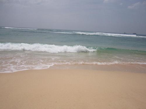 a beach with the ocean and a wave at White Surfing Beach Resort in Unawatuna