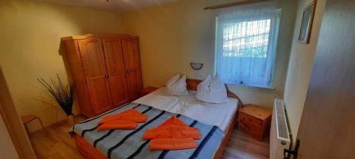 a small bedroom with a bed with orange pillows at Ferienwohnung Bergholz in Klein Zicker