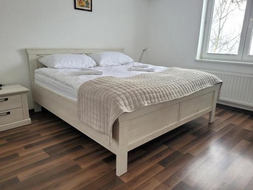 a white bed in a bedroom with a wooden floor at Apartman Studenac in Kiseljak