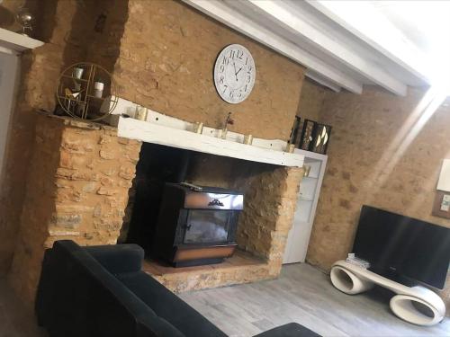 a living room with a stone fireplace and a tv at Les orchidées in Saint-Cybranet