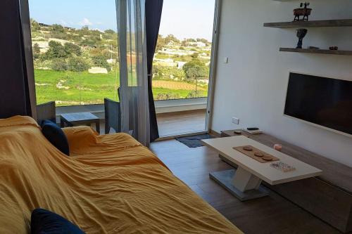 uma sala de estar com uma cama, uma televisão e uma mesa em Luxurious 2 bedroom apartment with country view em Marsaxlokk