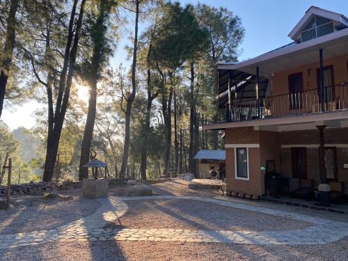a building with the sun shining through the trees at The Lodge at Wah, Kandbari in Pālampur