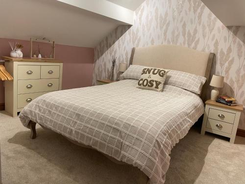 a bedroom with a bed with a blanket and a dresser at Swallows Rest in Leek