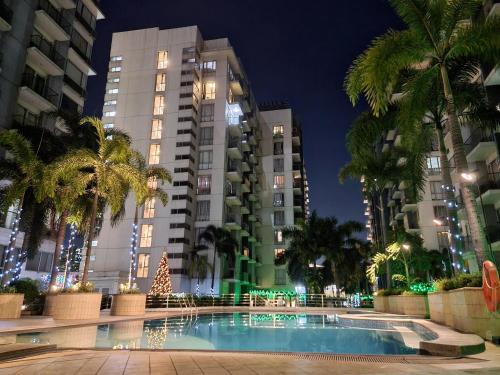 uma piscina em frente a edifícios altos à noite em One Palm Tree Villas Condo Across NAIA Terminal 3 em Manila