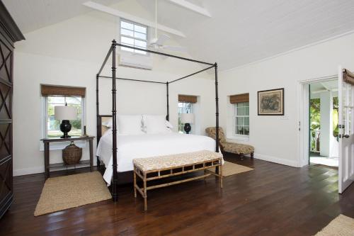 a bedroom with a canopy bed with a wooden floor at Buccaneer Hill Cottage cottage in Governorʼs Harbour