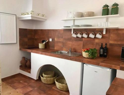 a kitchen with a sink and a counter with a fireplace at Varandas do Vale Furnazinhas in Castro Marim