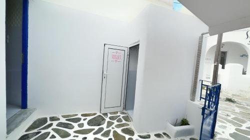 a bathroom with a door in a white wall at The Hot Pink Bike House in Parikia