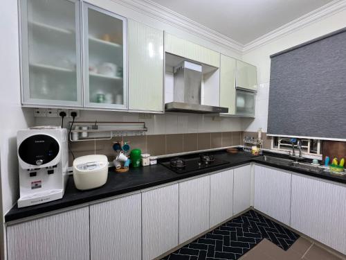 cocina con armarios blancos y encimera negra en 3R D'Latania Senawang, en Seremban