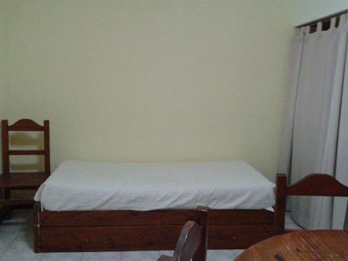 1 dormitorio con 1 cama con sábanas blancas y mesa en Alquilo dpto a cuadra de la playa en Necochea