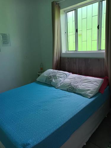 a bed with a blue blanket and a window at Pousada Decarli Executiva Aeroporto Florianópolis in Florianópolis