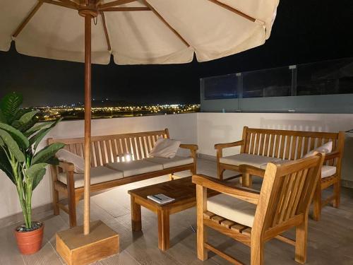 patio z 2 ławkami i parasolem w obiekcie Ocean Reef Triple Vanessa w mieście San Bartolo