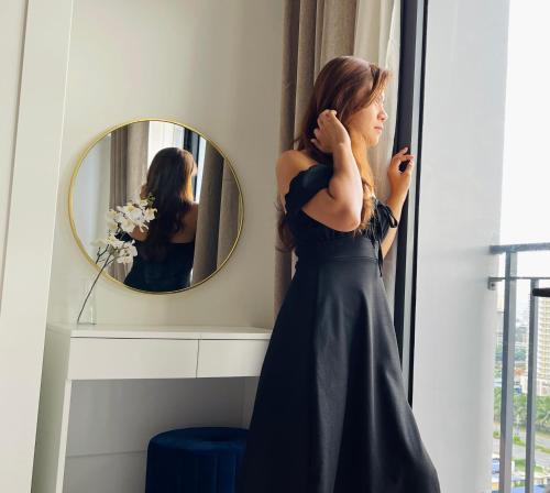 a woman in a black dress looking out a window at Sakan 5-Star Quality Condotel in Manila