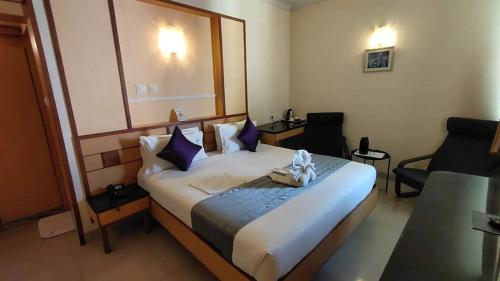 a hotel room with a large bed and a chair at Hotel Aishwaryaa in Erode
