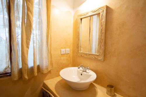 a bathroom with a white sink and a mirror at Rafiki Village in Watamu