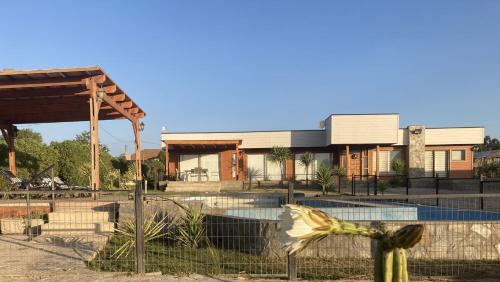 a building with a fence in front of a pool at Hermosa y comoda casa de campo con vista al valle in Limache