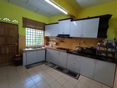 una cocina con armarios blancos y paredes verdes en D'Diana Homestay, en Port Dickson