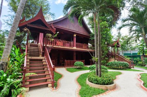 un complejo con palmeras delante en Royal Phawadee Village Patong - SHA Plus, en Patong Beach