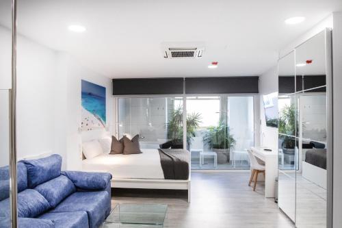 een slaapkamer met een bed en een blauwe bank bij Coccoloba Suites Corralejo in Corralejo