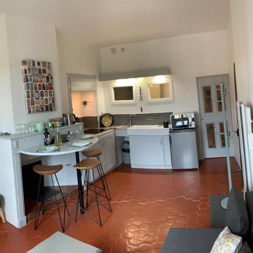 a kitchen with white cabinets and bar stools in it at Le Logis des Cascades1 in Moustiers-Sainte-Marie