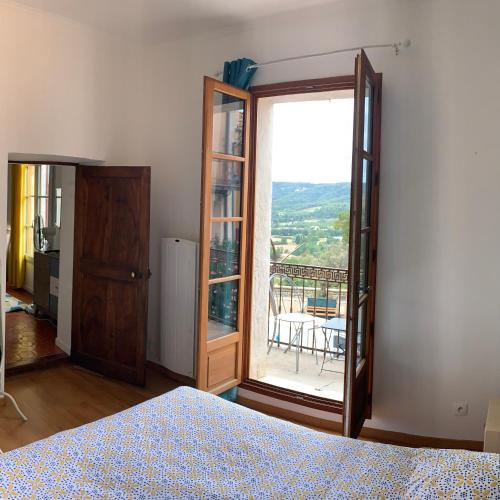a bedroom with a bed and a large window at Le Logis des Cascades1 in Moustiers-Sainte-Marie