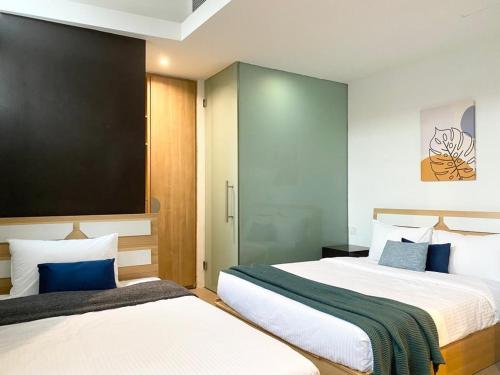 2 Betten in einem Hotelzimmer mit blauen Akzenten in der Unterkunft The Assembly Place, Hotel at Veerasamy in Singapur